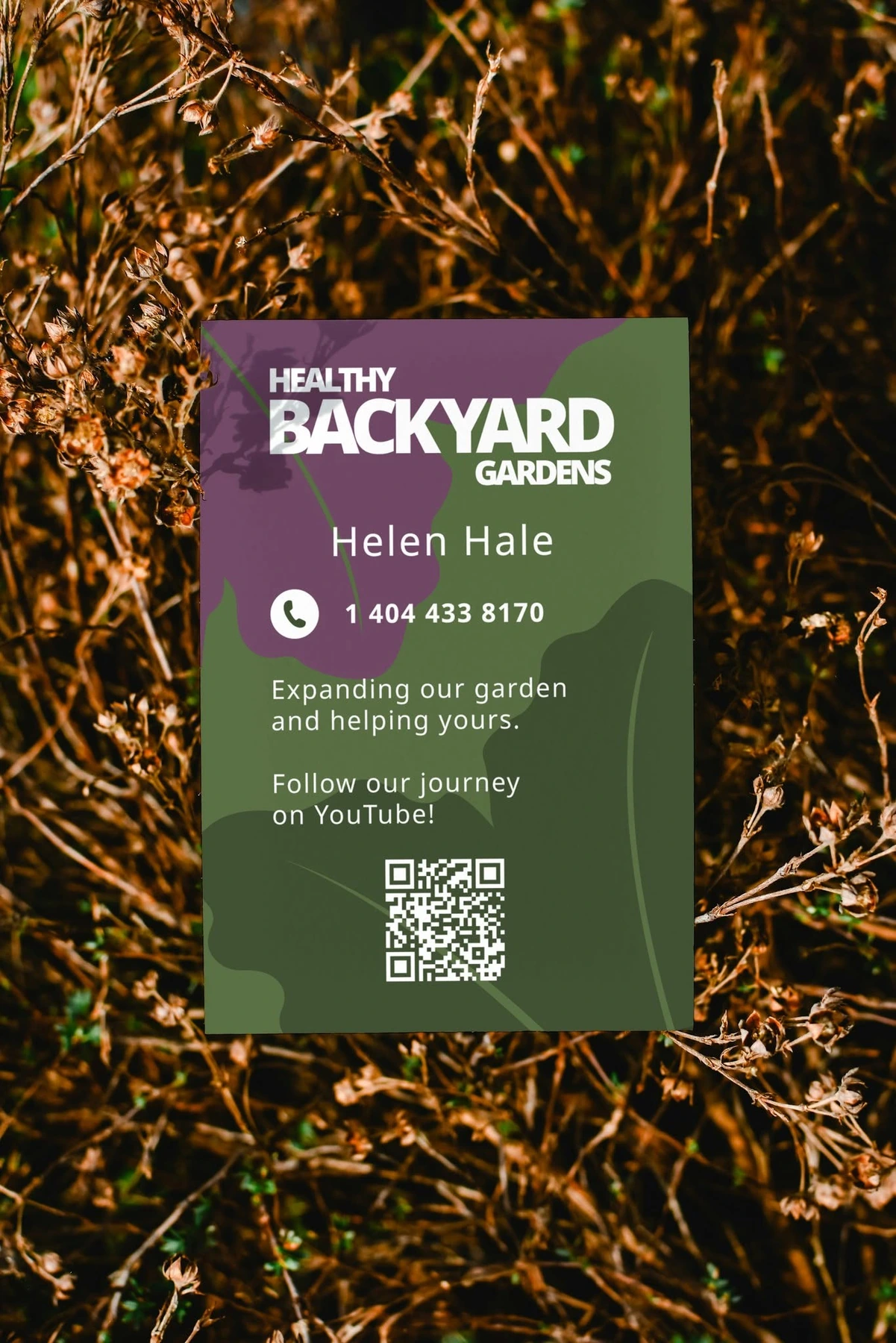 Healthy Backyard Gardens promotional card photographed in a garden setting